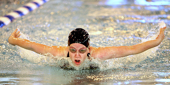 A swimmer in a pool performing the breast stroke