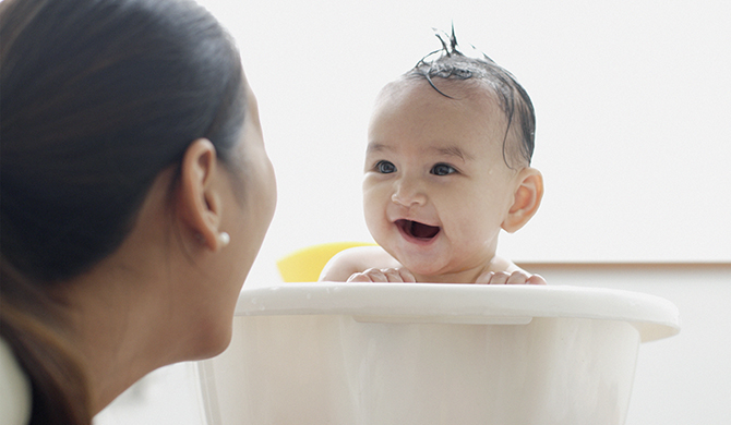 Baby having a bath and smiling at his mom