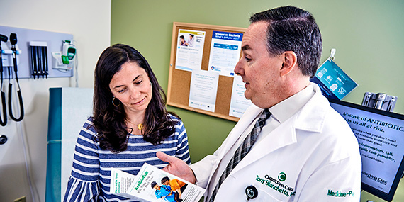 A doctor talks to a patient while showing her a pamphlet about proper use of antibiotics.