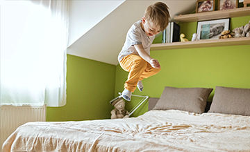 Happy, healthy child jumping on a bed