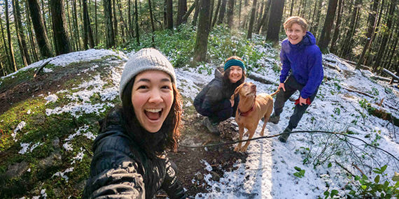 Three people and a dog hike in the snowy woods.