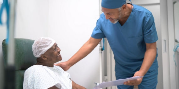 Un enfermero que sostiene una carpeta con sujetapapeles y habla con un paciente