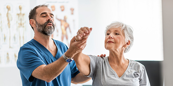 Un cuidador trabaja con una mujer mayor con osteoporosis