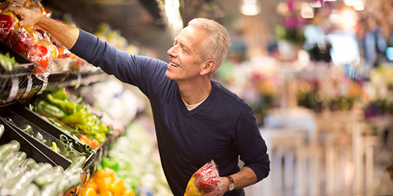 Un hombre mayor que selecciona verduras en una tienda de comestibles