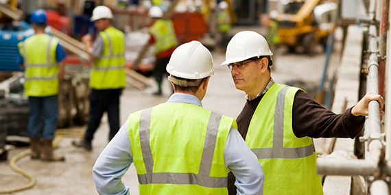 Trabajadores de la construcción en un lugar de trabajo con cascos y chalecos de seguridad
