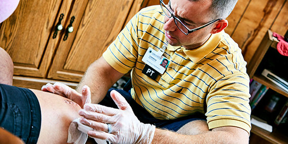 Un fisioterapeuta que examina a un paciente después de una cirugía de reemplazo de rodilla