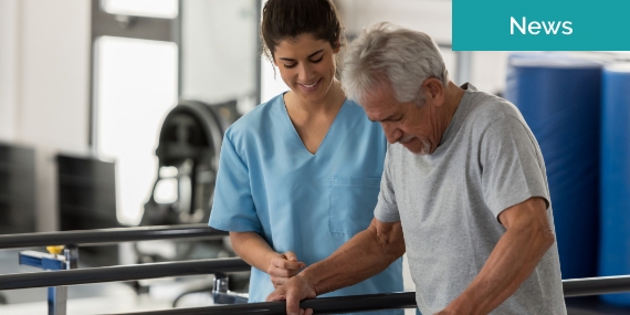 Un fisioterapeuta que ayuda a un paciente de edad avanzada mientras camina usando las manos para soportar su peso en las barras