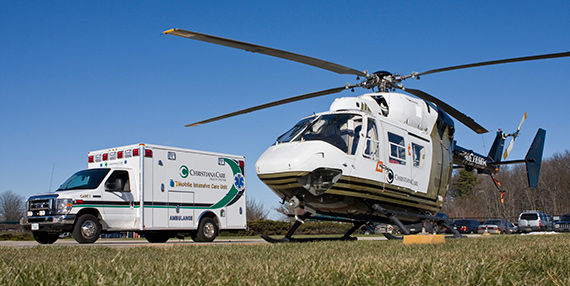 Una ambulancia y un helicóptero de ChristianaCare estacionados uno al lado del otro.