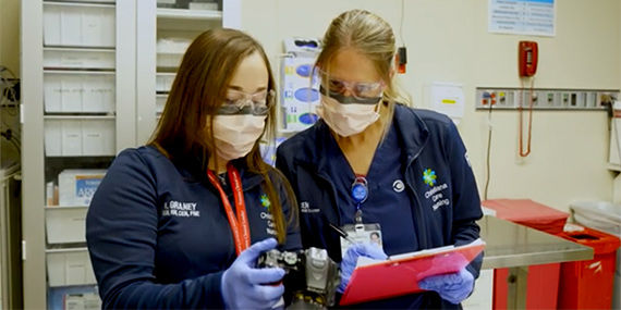 Dos examinadores de enfermería forense toman notas a partir de imágenes en una cámara digital.