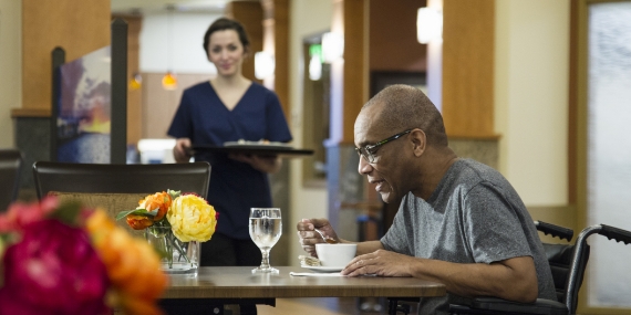 Hombre de edad avanzada comiendo en la cafetería de un hospital
