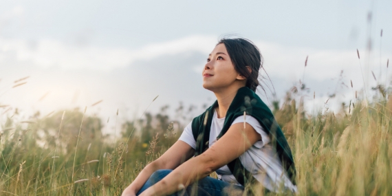 Una mujer joven que disfruta de la naturaleza sentada en el prado