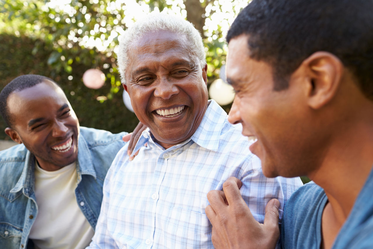 A senior man talking with his adult sons in a garden, close up
