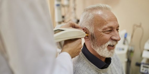 Audiologist examining ear of a senior man