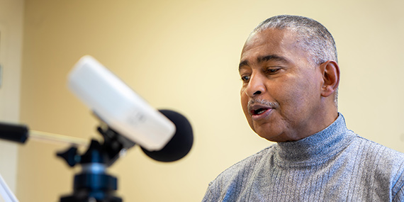 A man speaks into a microphone as part of a speech therapy exercise.