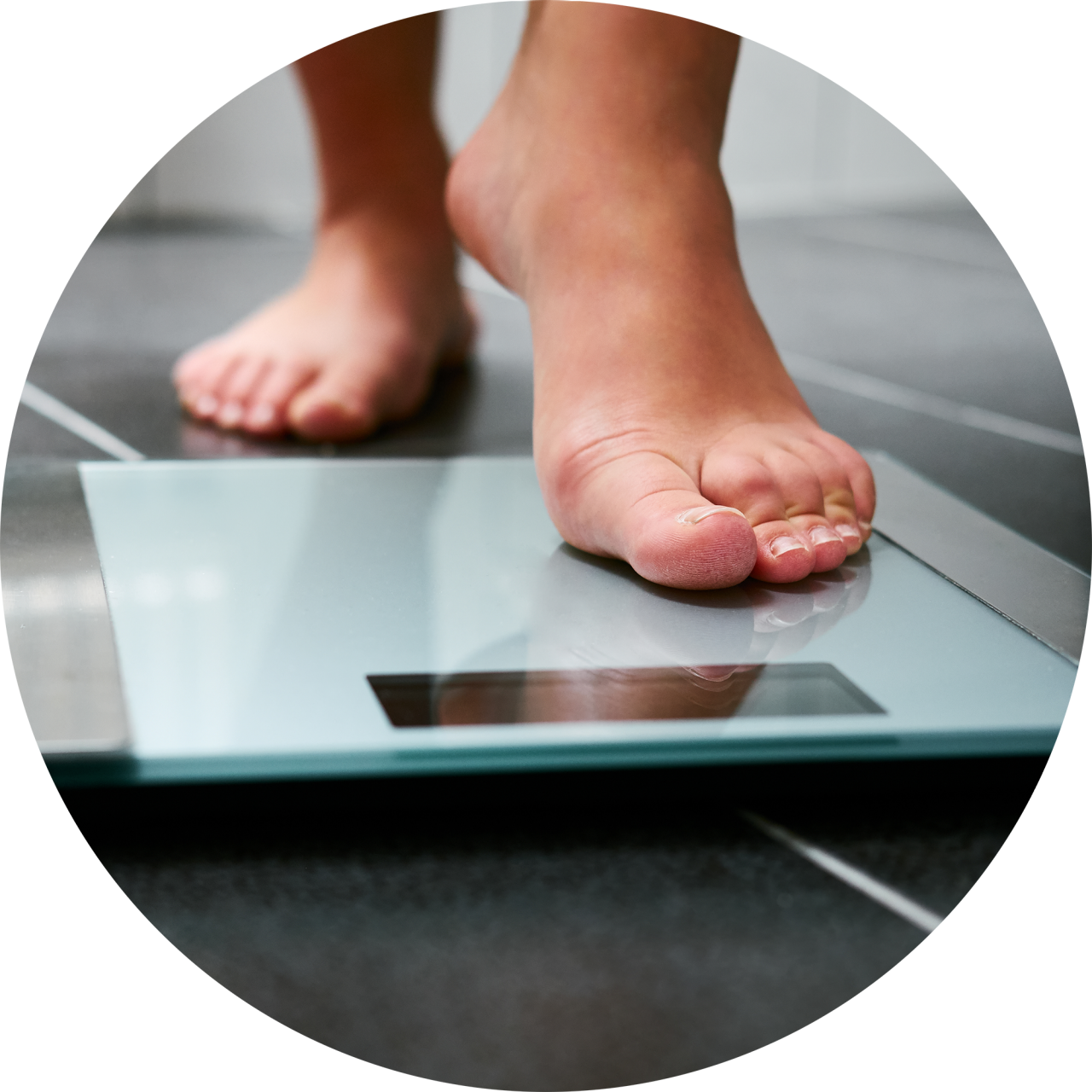 A closeup of a bathroom scale as a person steps onto it