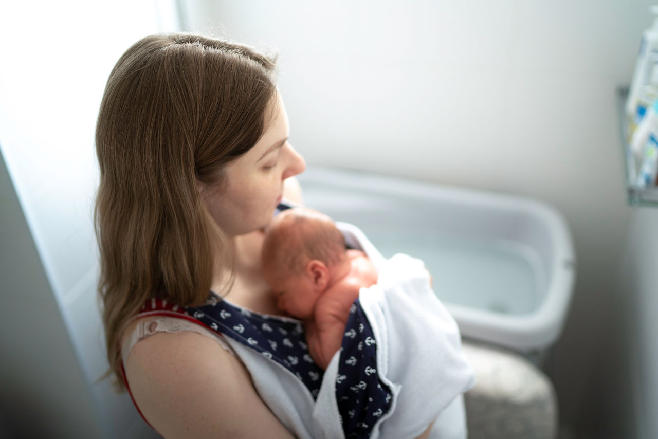 Mother holding her newborn at bathroom