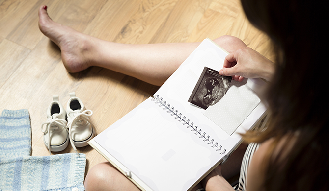 Woman looking ultrasound scan in notebook