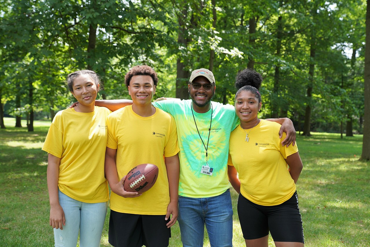 Group photo of three young people with their football coach