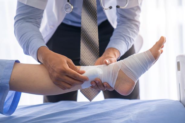 El médico realiza un vendaje de la pierna del paciente