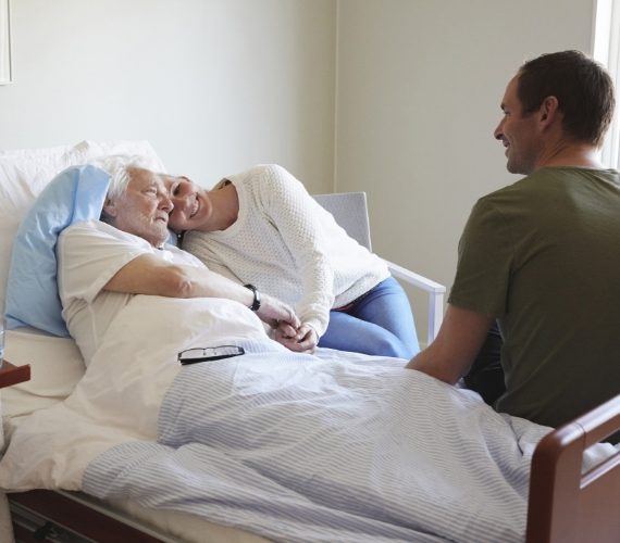 alt=Hombre de edad avanzada recibe la visita de hija y de su hijo en un hospital