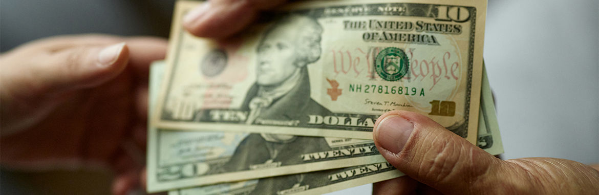 Close up of unrecognizable man paying someone with dollars.