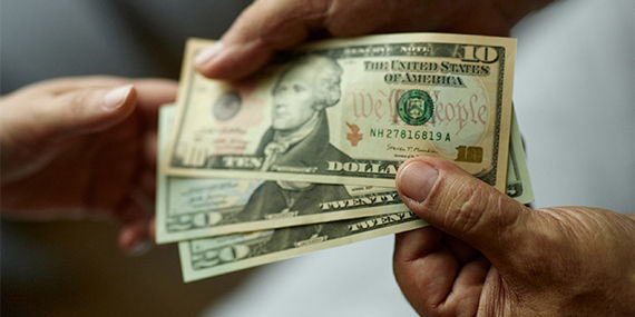 Close up of unrecognizable man paying someone with dollars.