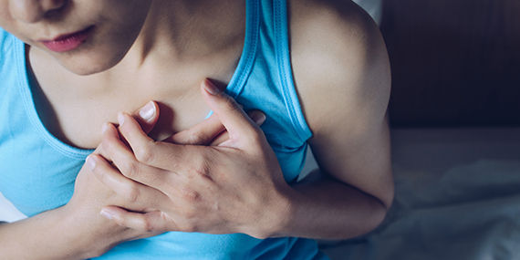 A woman holds her chest in distress from heart failure