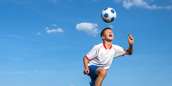 A boy bounces a soccer ball on his head.