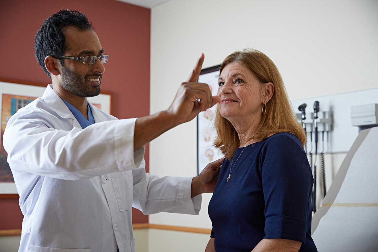 A doctor leads a stroke victim through therapy and assessment.