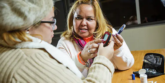A nurse assists a patient with a diabetes test.