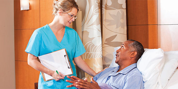 A doctor speaks to her patient, who is lying in a hospital bed