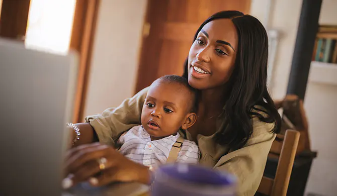 Mother with child in lap looking at laptop