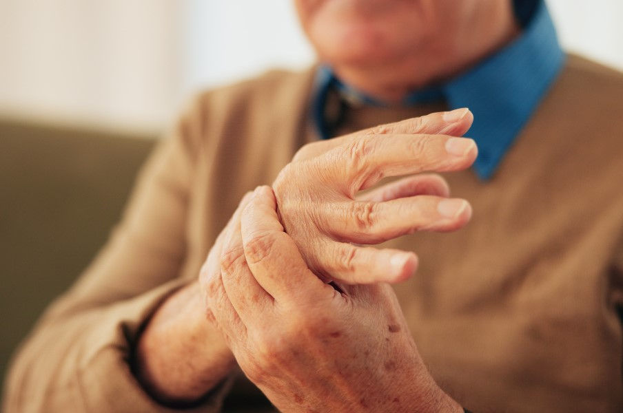 An older man rubs the back of his hand