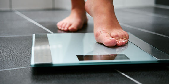 A closeup of a bathroom scale as a person is stepping onto it