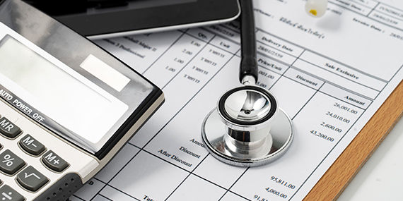 A calculator and a stethoscope lay on a medical care invoice