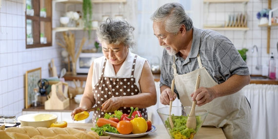 Una pareja de ancianos que prepara comida en la casa