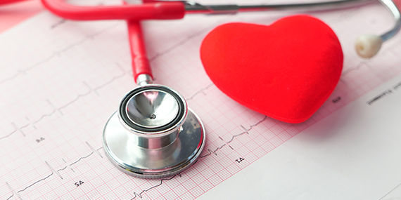 Un estetoscopio y un juguete en forma de corazón colocados en una tabla de cardiogramas