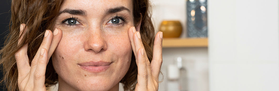 Una mujer presiona los dedos contra la piel debajo de los ojos