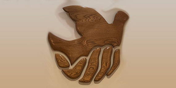 Una escultura de madera que representa una mano que sostiene una paloma