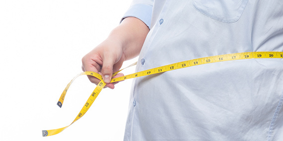 Un hombre obeso con una cinta métrica envuelta alrededor de su abdomen.