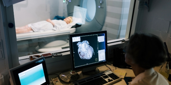 Un técnico de laboratorio ayuda a una paciente mientras la colocan dentro de una máquina de IRM
