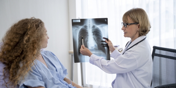 Una médica que revisa una radiografía en la habitación de un paciente