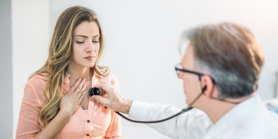 Un médico que examina el pecho de una mujer joven