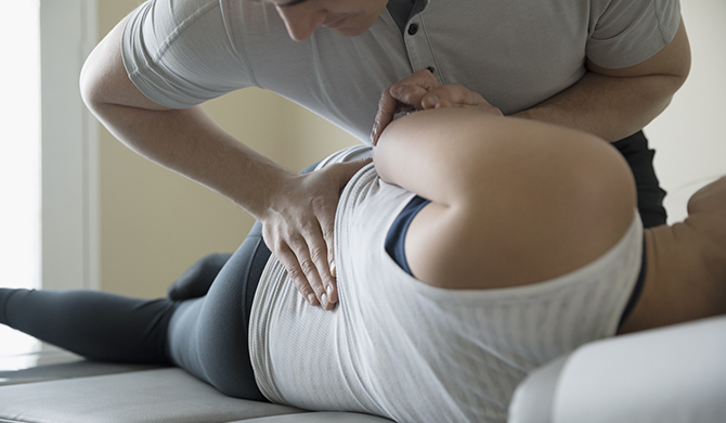 Chiropractor adjusting woman on clinic examination table