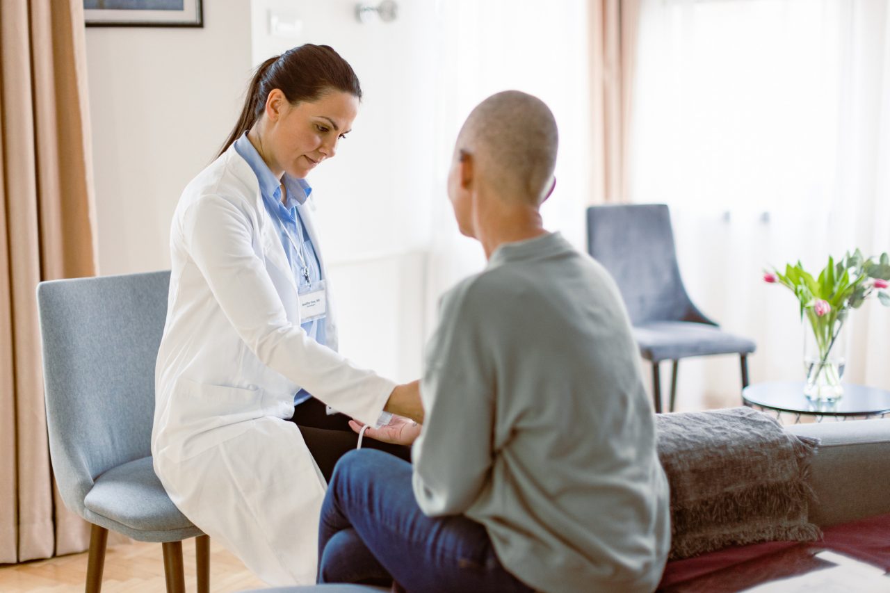Woman with cancer having home session with doctor