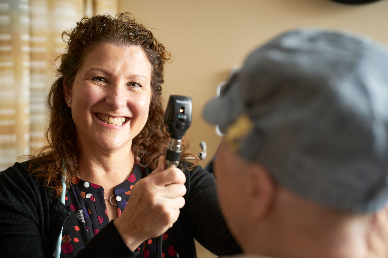 A medical professional performs an eye exam on a patient in an exam room
