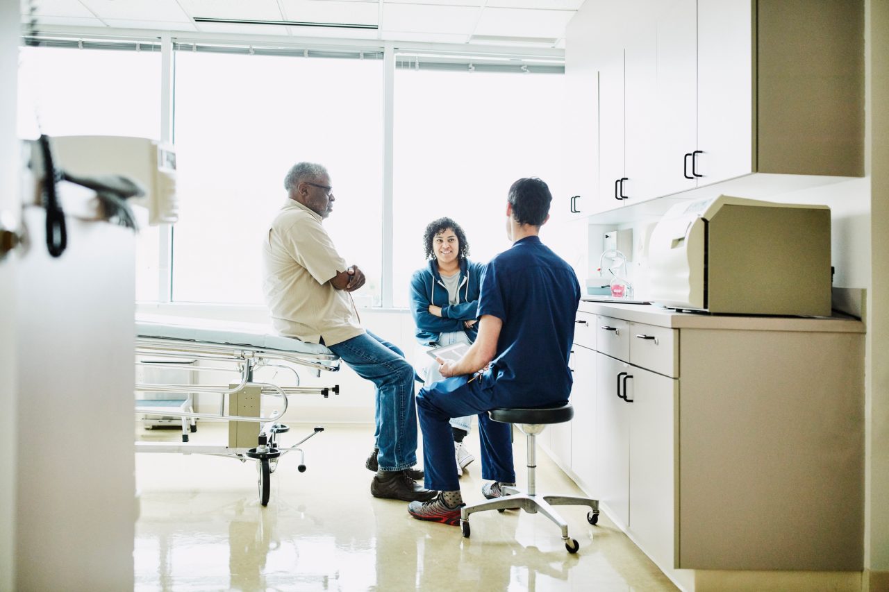 Male patient and daughter consulting with male nurse 