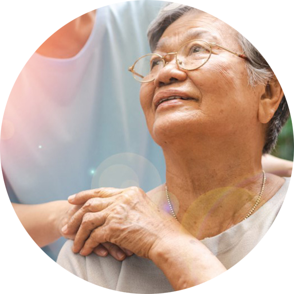 A senior Asian woman looks up at her daughter while holding her hand resting on her shoulder