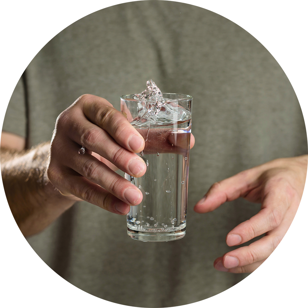 Water splashes from a glass in the hand of a man with tremor