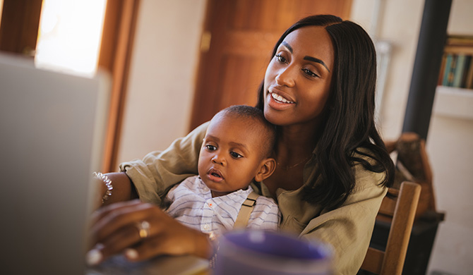 Mother with child in lap looking at laptop